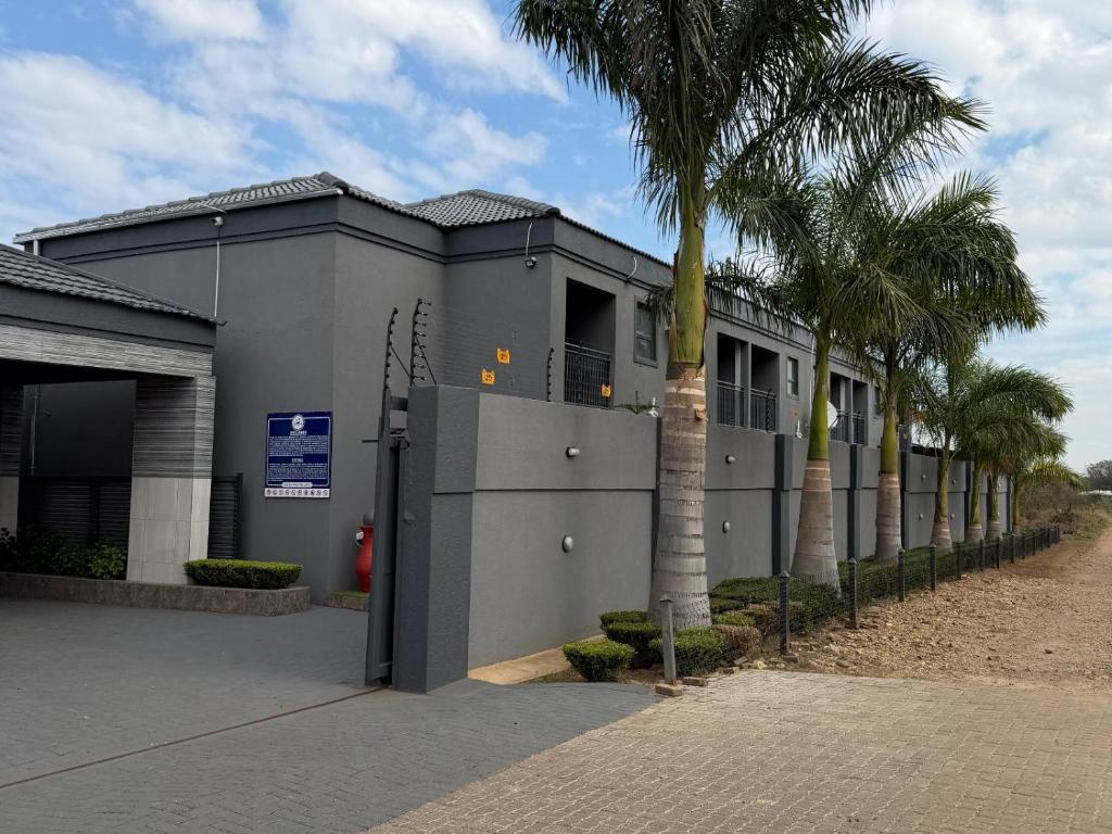 a building with palm trees in front of it at Giyani Shamba Lodge in Giyani