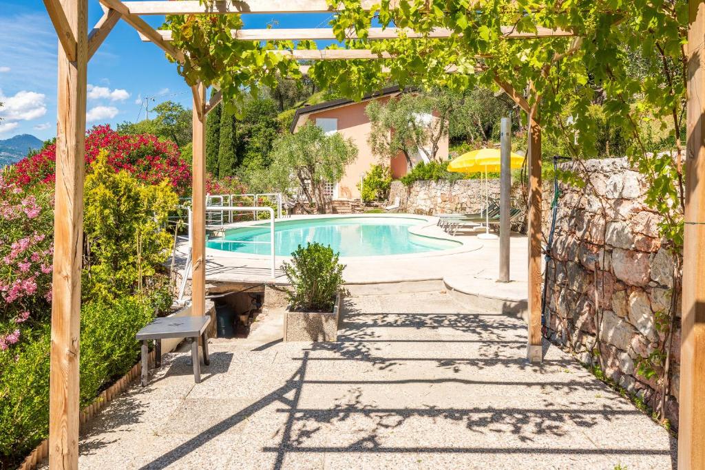 a pool in a garden with a bench and trees at Villa Incanto Adults Only in Brenzone sul Garda
