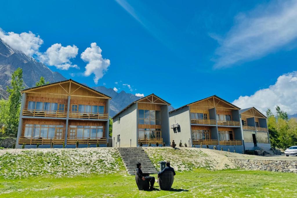 two cats sitting on the grass in front of a building at Meechung Resort in Skardu