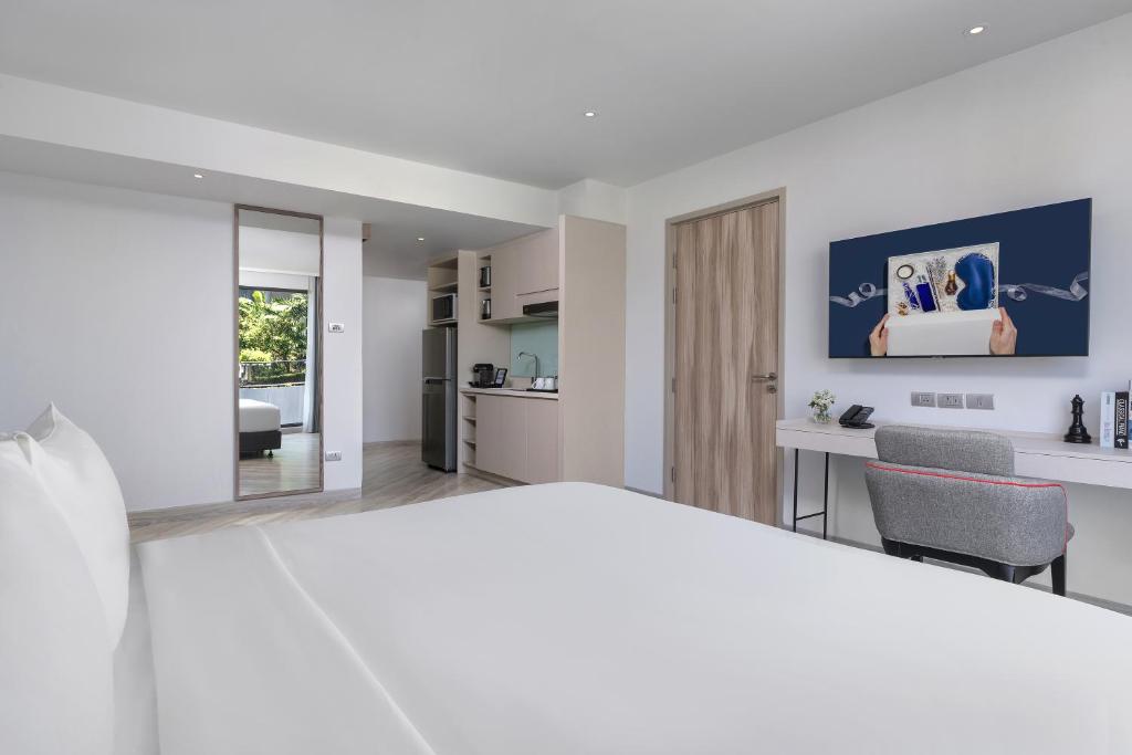 A bedroom opening onto a compact kitchenette and a separate sitting area.
