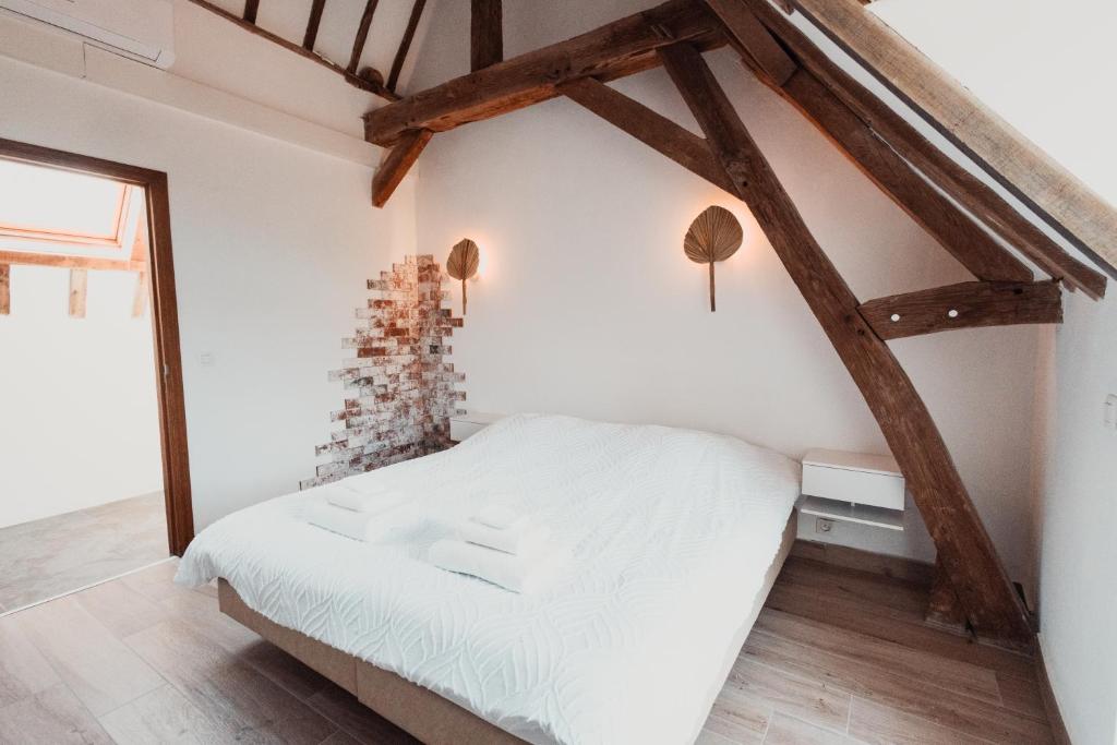 a bedroom with a white bed and wooden beams at La MASSERIA in Thuin