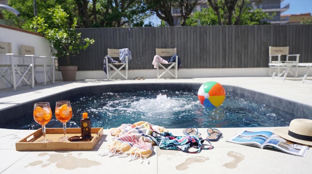 a swimming pool with a beach ball and two wine glasses at B&B Hotel Villa Nora in Bellaria-Igea Marina