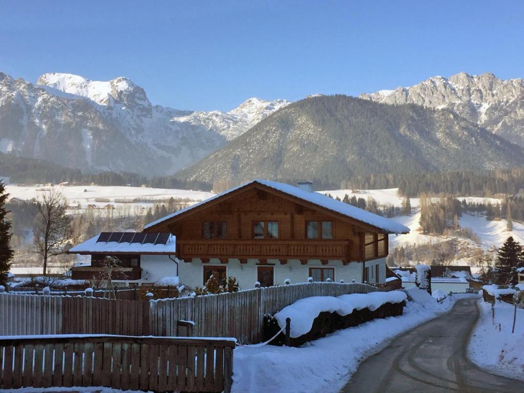 a log cabin in the snow with mountains in the background at Ferienwohnung GIA in Haus im Ennstal
