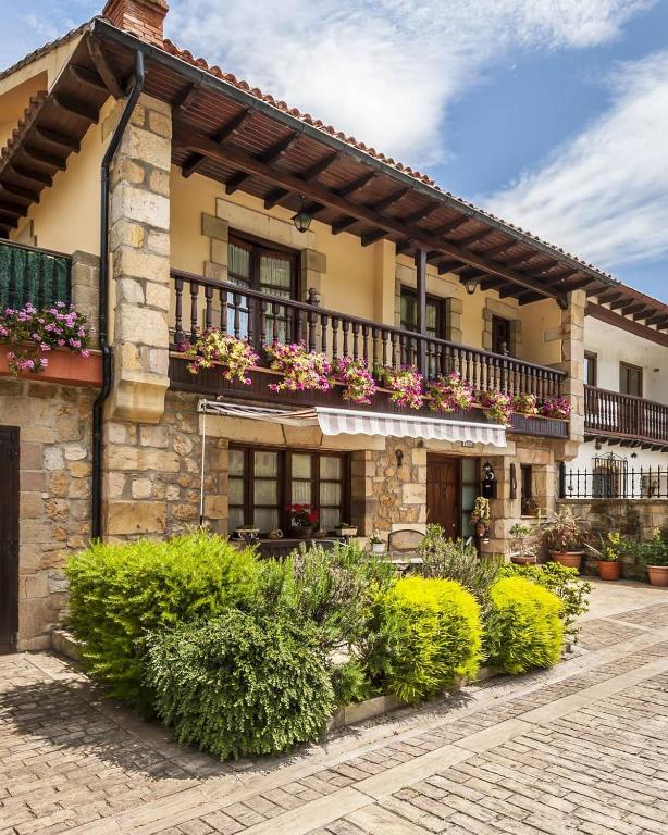 a building with a balcony with flowers on it at La Chimenea Cantabra in Oreña