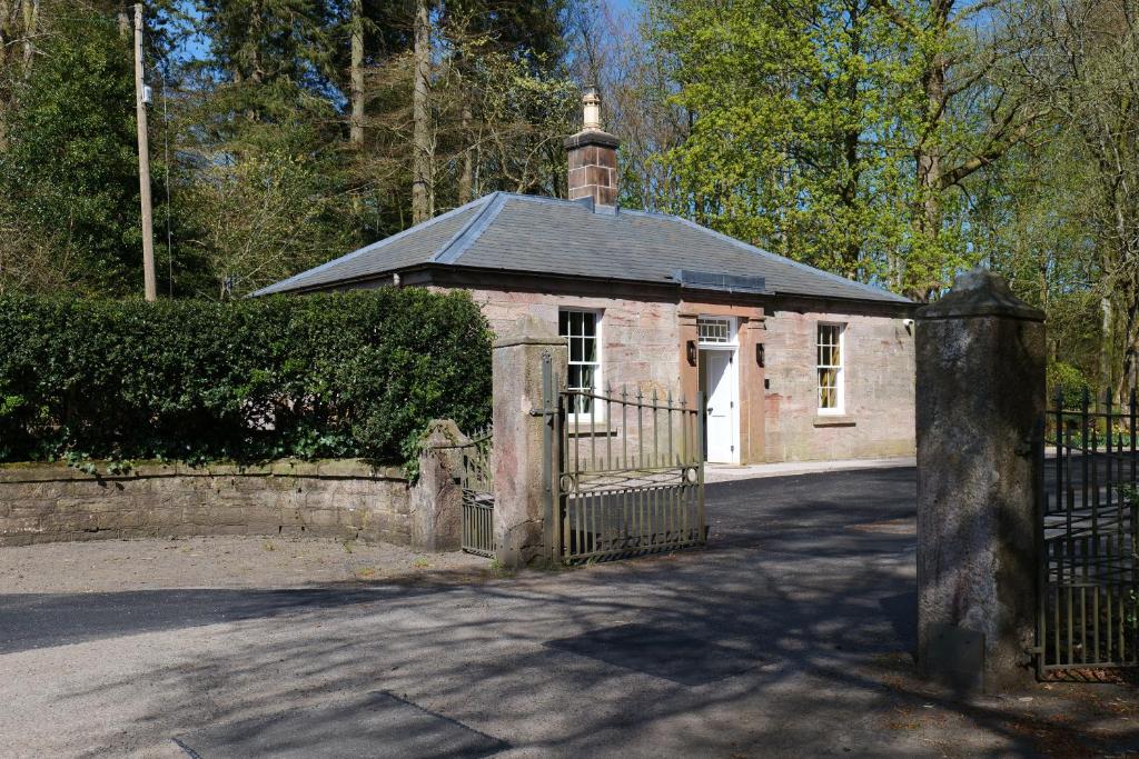 a small brick building with a gate and a fence at The Lodge at Dabton House in Carronbridge