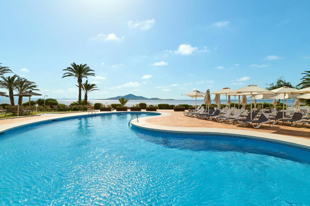 a large swimming pool with chairs and umbrellas at AluaSun Doblemar in La Manga del Mar Menor