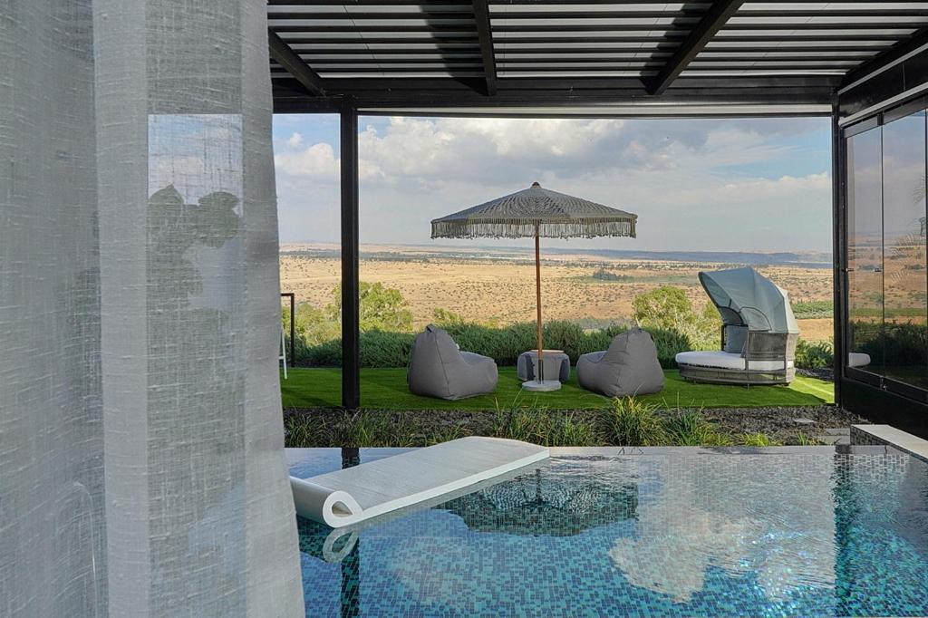 a house with a swimming pool and an umbrella at Y HOUSE SUITES in Mishmār Hāyardin