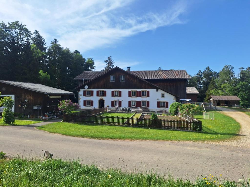 a large white house with a fence and a road at Chambres d'hôtes Les Fontaines in Tramelan