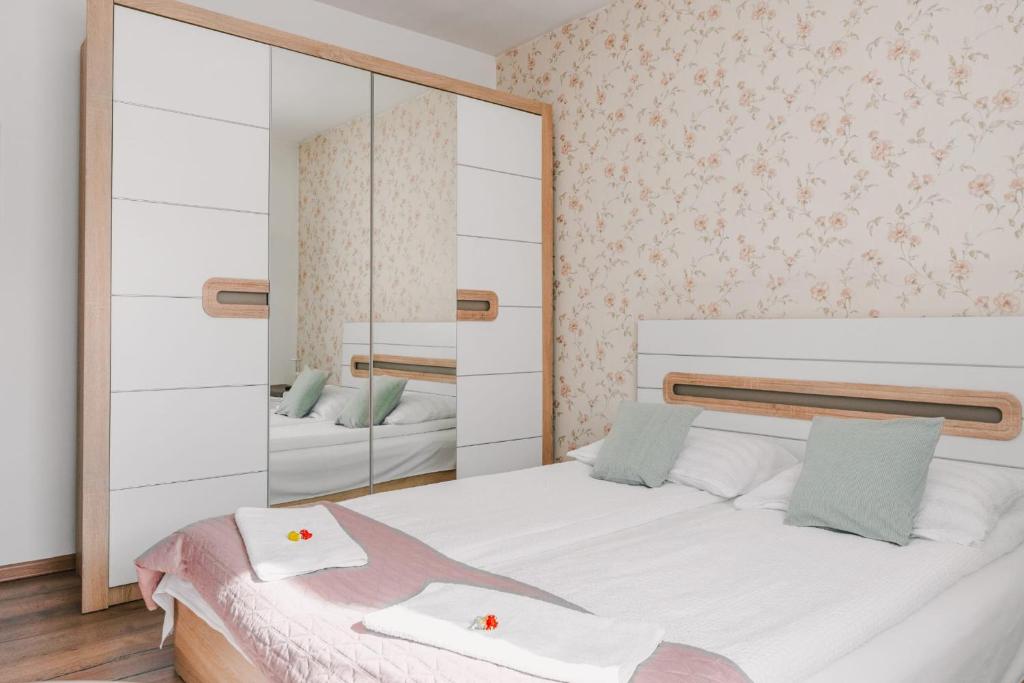 a bedroom with a white bed and a mirror at Apartament de închiriat in Borsec