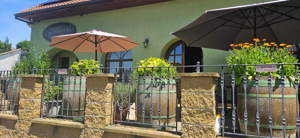 a fence with two umbrellas in front of a building at Penzion Bernardýn in Bořetice