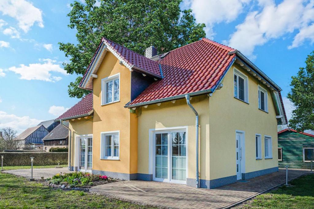 a yellow house with a red roof at Ferienwohnung Sonneneck in Kachlin
