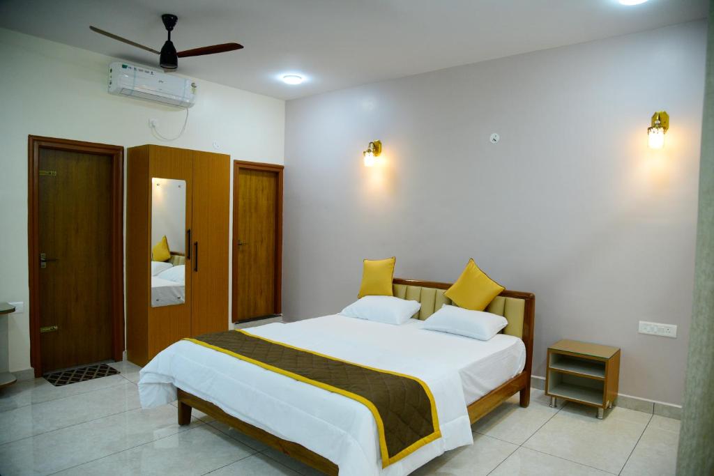 a bedroom with a large white bed with yellow pillows at Aldur Residency in Aldūr