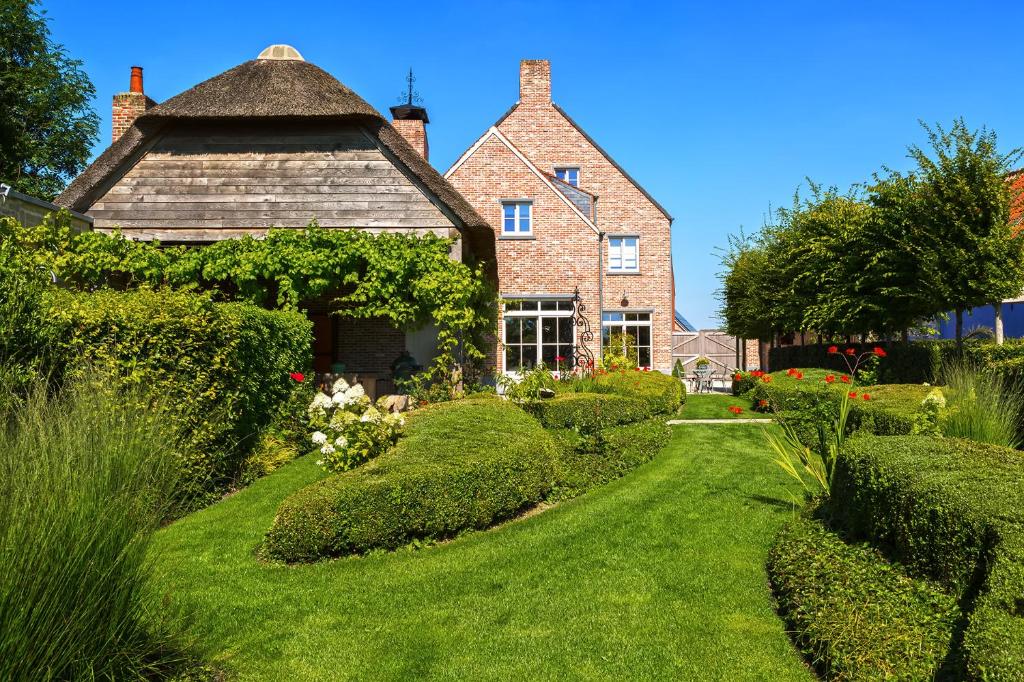 une maison ancienne avec un jardin en face dans l'établissement B&B Vinedo, à Zele