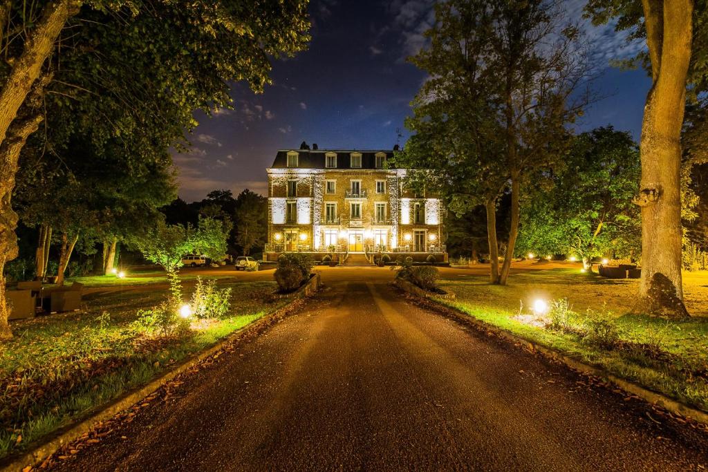 a large house with lights on a road at Logis Hôtel - Le Manoir de Sauvegrain in Saint-Lambert