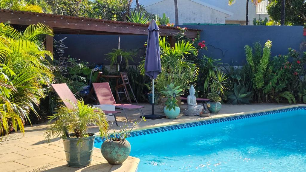 a swimming pool with plants and an umbrella at Ti kaz cheu nous in Saint-Louis