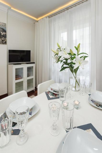 a dining room with a white table with a vase of flowers at Apartament Abrahama in Gdynia