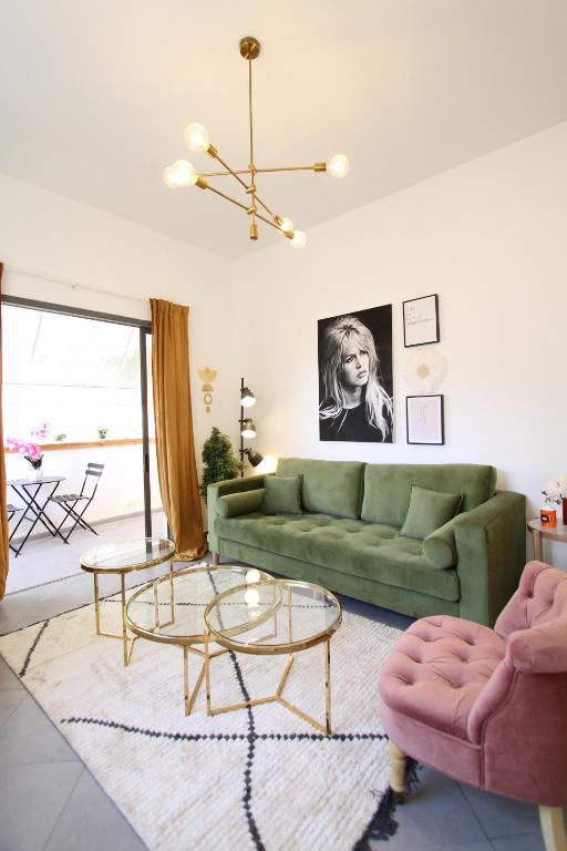 a living room with a green couch and two tables at Design & Balcony In City Center By Feelhome in Tel Aviv