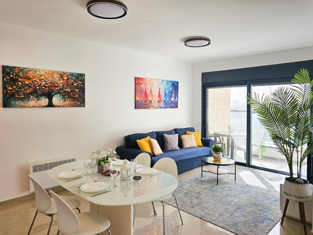 a living room with a blue couch and a table at Mamad Family Friendly New Condo By Feelhome in Yerushalayim