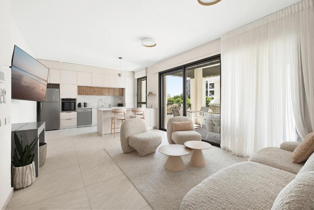 a living room with a couch and chairs and a kitchen at Mamad New With Terrace Next To Park By Feelhome in Tel Aviv