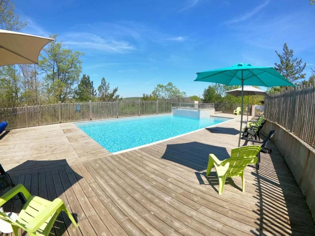 a swimming pool with green chairs and an umbrella at Camping 2 étoiles - Piscine - ccbgcid in Belloc