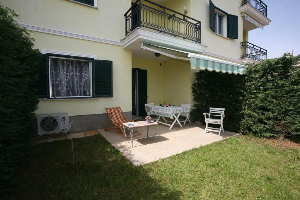 eine Terrasse mit Tisch und Stühlen vor einem Haus in der Unterkunft Apartman Halugica in Lovran