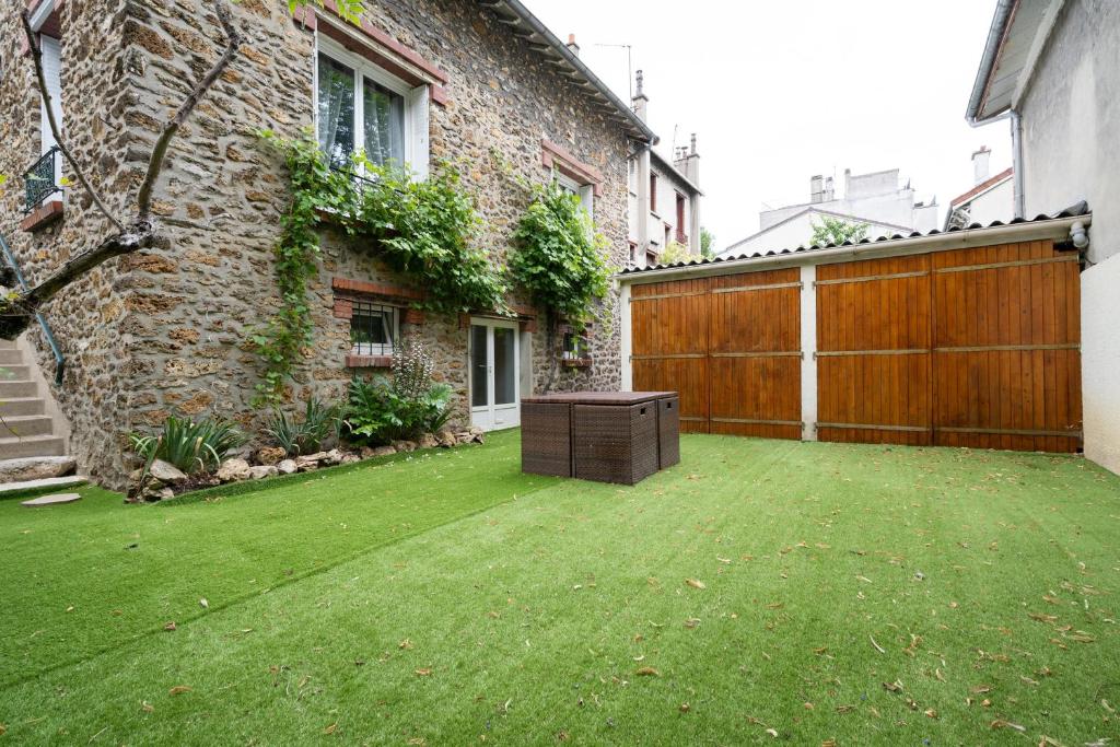 a yard with a wooden fence and a house at L'Oasis Familiale Arborée - Welkeys in Vincennes