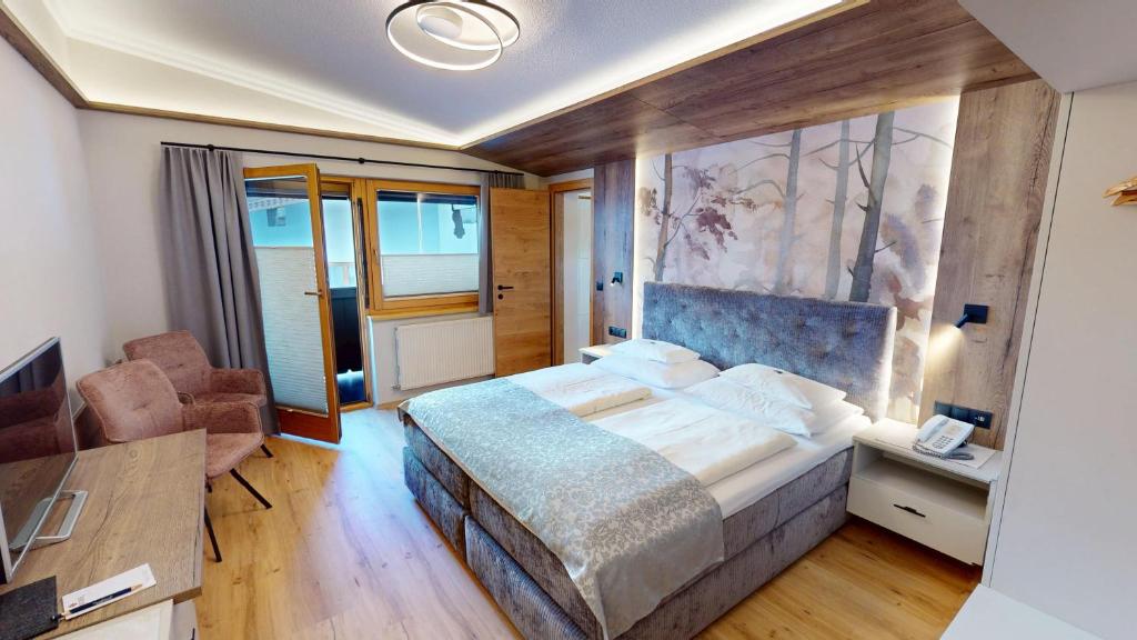 a bedroom with a large bed and a desk at Hotel-Garni Jakober - B&B und Appartements in Tux