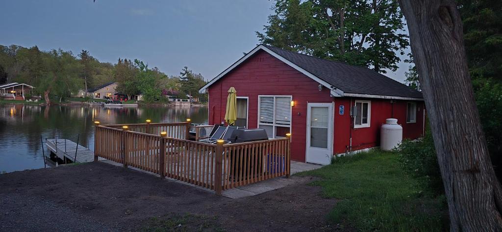 a small red house with a porch next to a lake at Trent River Cottages in Hastings