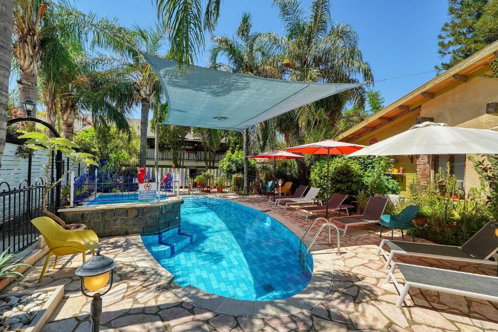 a swimming pool with chairs and umbrellas at Out of Africa Resort in Had Nes