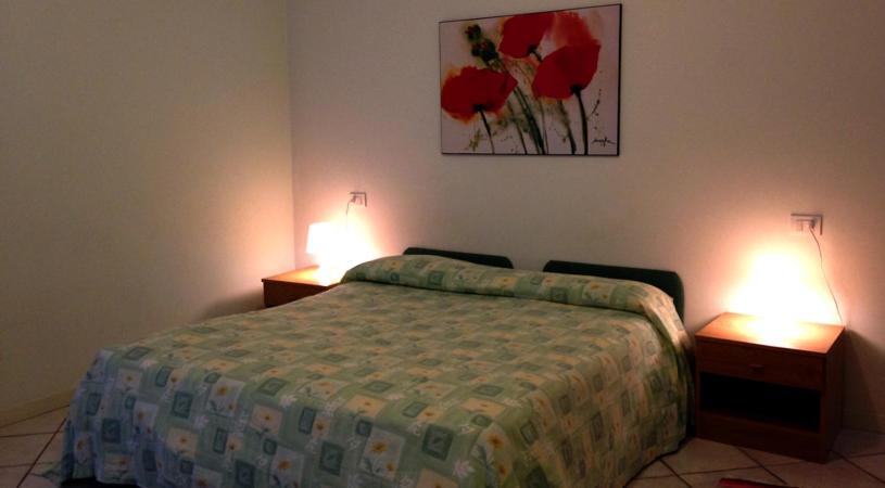 a bedroom with a bed and two lights on two tables at Green Village Accommodations in Colico