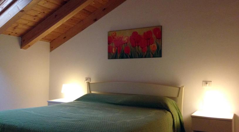 a bedroom with a bed with a painting on the wall at Green Village Accommodations in Colico