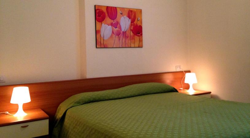 a bedroom with a green bed with two lamps at Green Village Accommodations in Colico