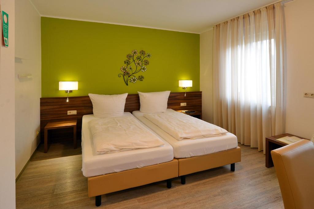 a bedroom with a bed with a green wall at Hotel L' Angolo in Trier