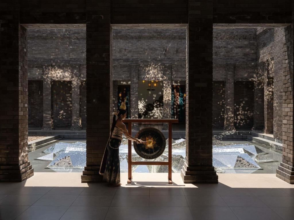 a woman is standing in a room with a wheel at Avista Hideaway Phuket Patong - MGallery in Patong Beach
