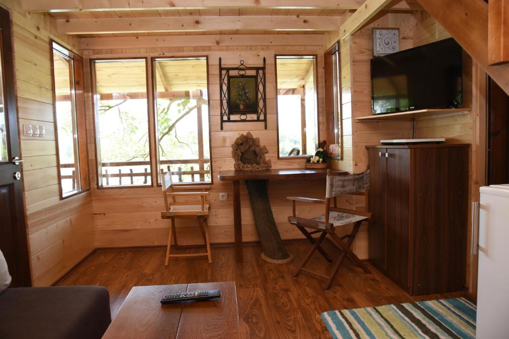 ein Wohnzimmer mit einem Tisch und einem TV in einer Hütte in der Unterkunft Holiday Home Kućica Na Drvetu in Banja Koviljača