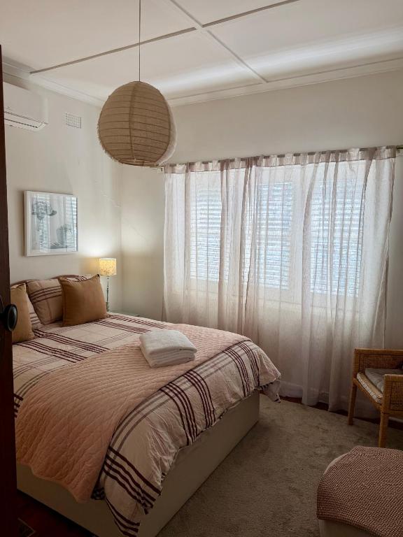 a bedroom with a bed and a large window at Darlow Cottage in Wagga Wagga