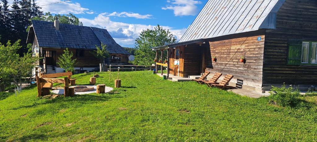 a wooden cabin with a grass yard next to a building at Domacinstvo Obradovic Nadgora in Nadgora