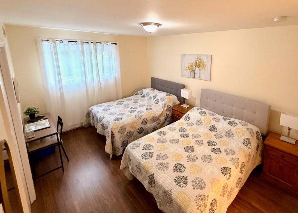 a bedroom with two beds and a table and a window at Gîte de la vallee in Coaticook