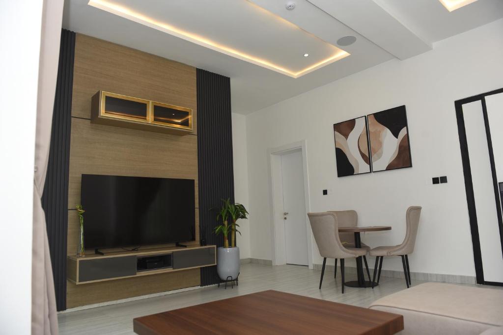 ein Wohnzimmer mit Fernseher und Tisch in der Unterkunft White Pole Apartments in Abuja