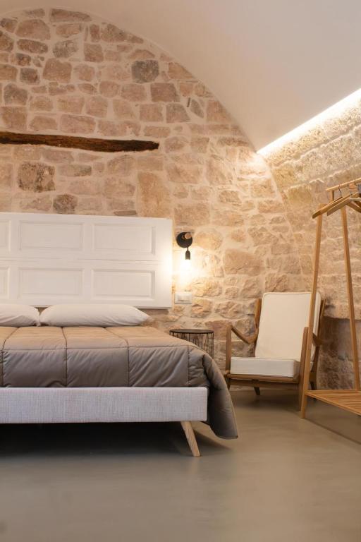 a bedroom with a bed and a stone wall at Pepenero Apulian Rooms in Noci