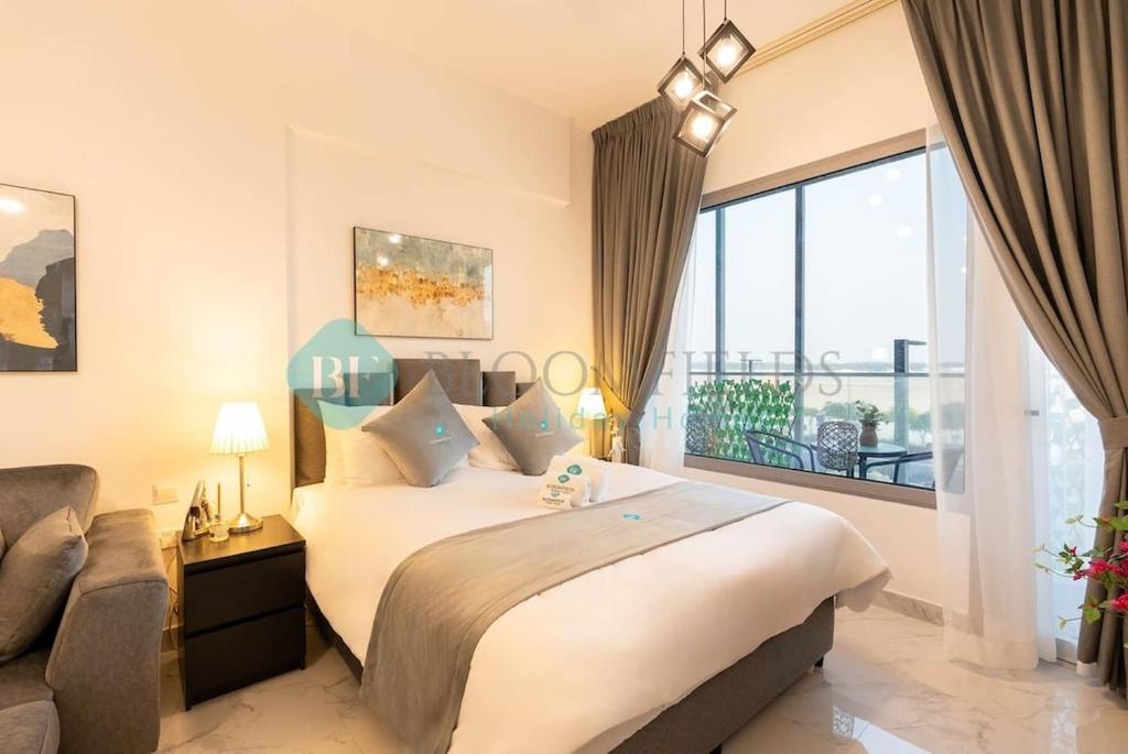 a bedroom with a large bed and a large window at Bloomfields Studio in Oasis Masdar in Abu Dhabi