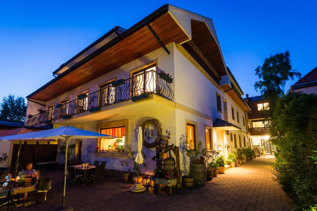 a building with a patio with tables and an umbrella at Pension Julia & Haus Elisabeth - Wallner's Hofheuriger & Weinhof in Mörbisch am See