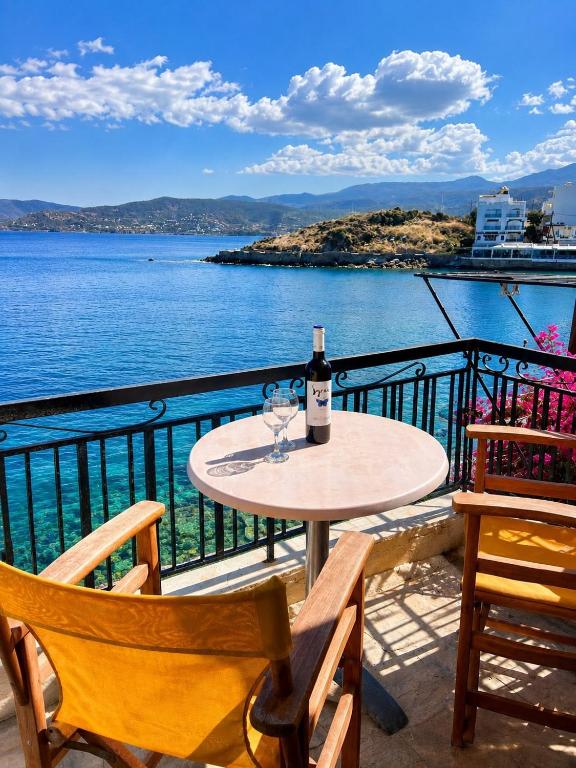 a table with a bottle of wine and two chairs at Horn Agios Nikolaos in Agios Nikolaos