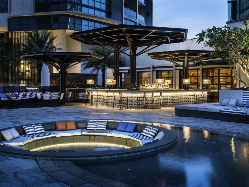 A courtyard pool area with a circular sunken feature, loungers, and a poolside bar.