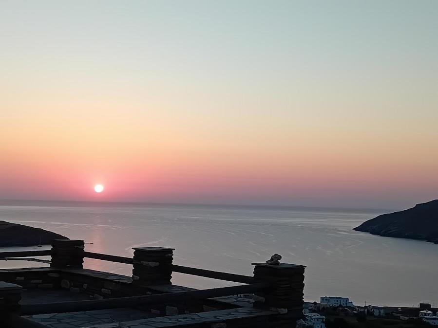 a sunset over the water with a bird on a fence at Liopi Village Andros in Órmos