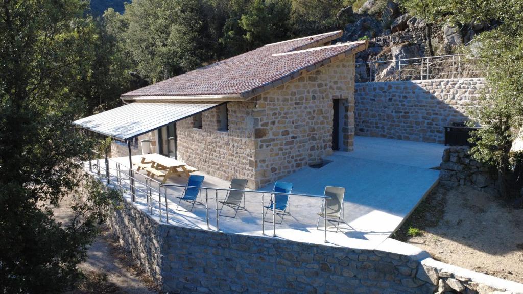 a small stone house with chairs and a table at Gite Les Oliviers d'Ardèche in Chalencon