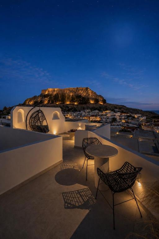 a rooftop patio with chairs and a table at night at Noema Lindos - Agapitos Apartment in Lindos