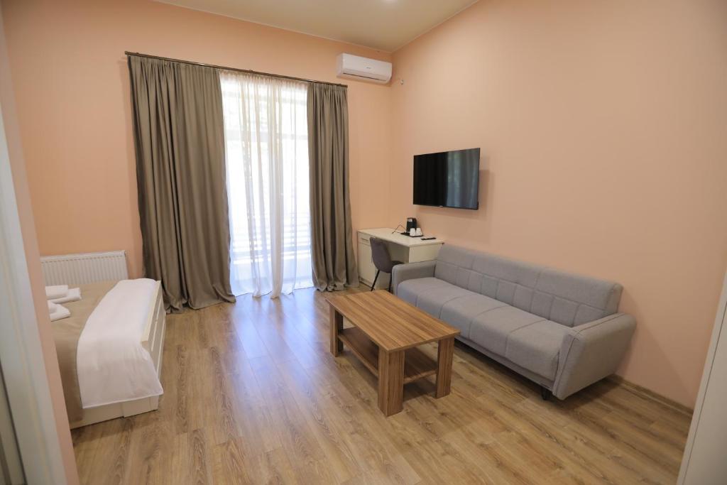 a living room with a couch and a table and a television at Prime Heaven in Chiatʼura