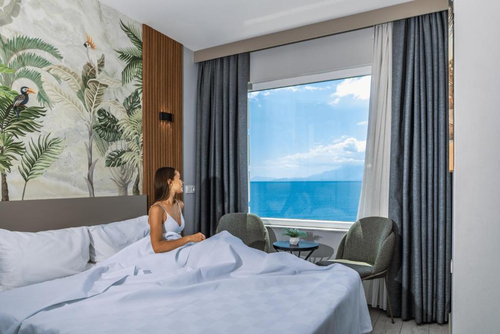 a woman sitting on a bed looking out a window at Letstay Panorama Suites in Antalya