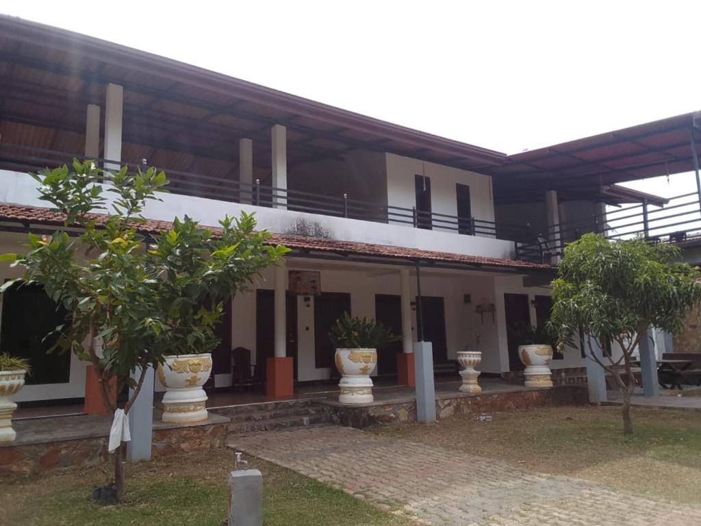 a building with potted trees in front of it at Kataragama Brain Hotel in Kataragama